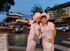 Two ladies in costume pose in front of the Downtown Pleasanton arch at Pleasanton, Ca Halloween Brew Crawl