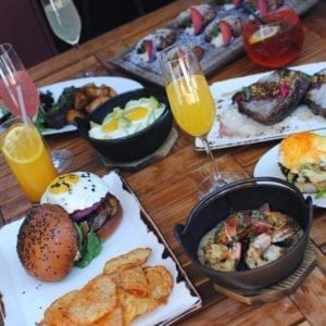 brunch spread including mimosa a burger with eggs and other foods