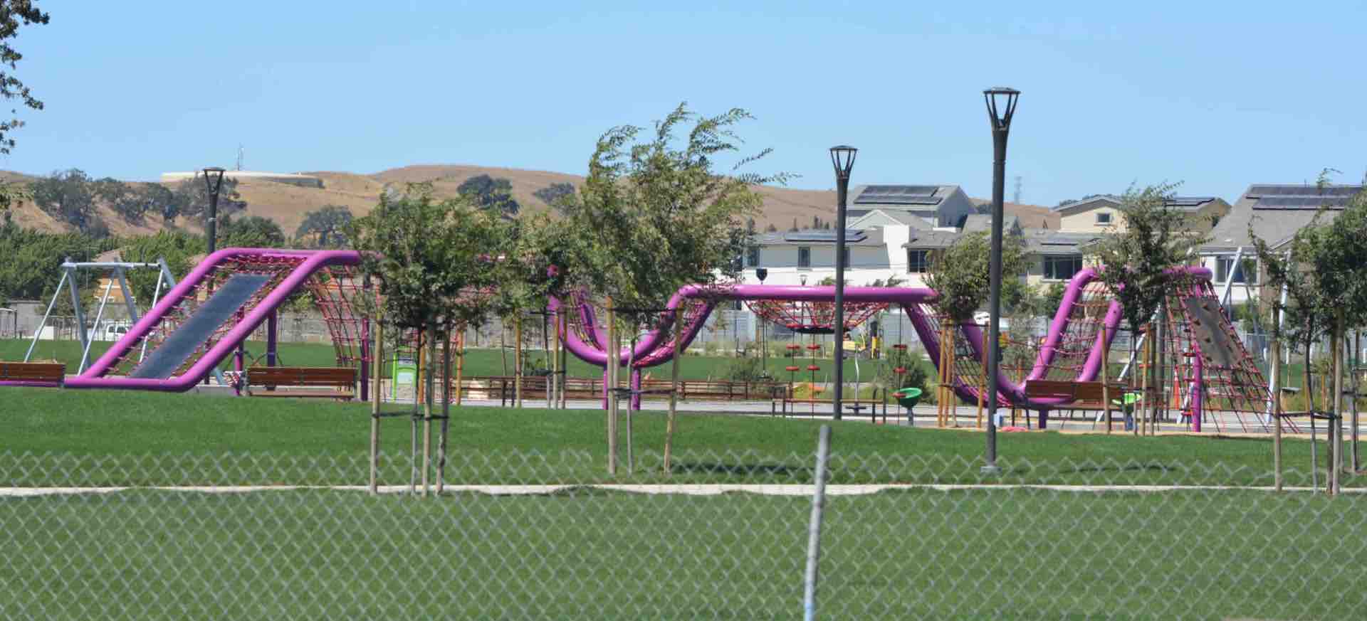 Purple playground element surrounded by green grass at a local park.