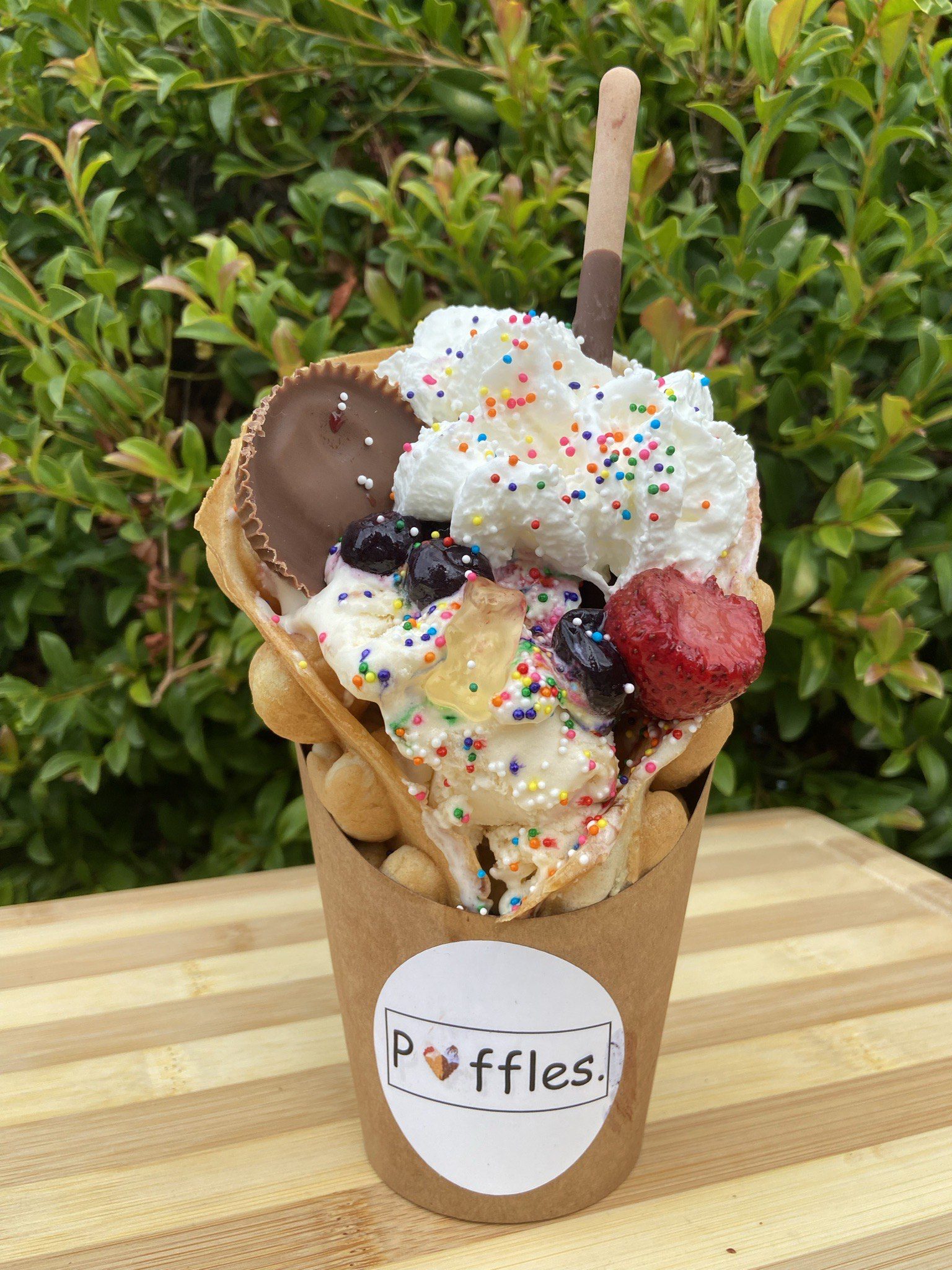 Puffy waffle cone full of ice cream and covered in a variety of colorful toppings.