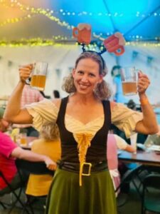 woman in traditional german attire celebrating oktoberfest by holding two beers