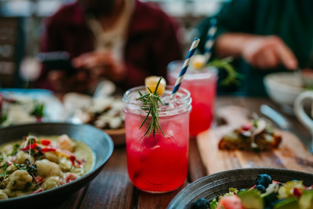 close-up image of a red beverage with rosemary and lemon wedge