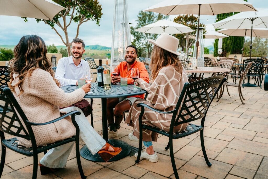 four friends at a table overlooking livermore valley wine country at las positas vineyards